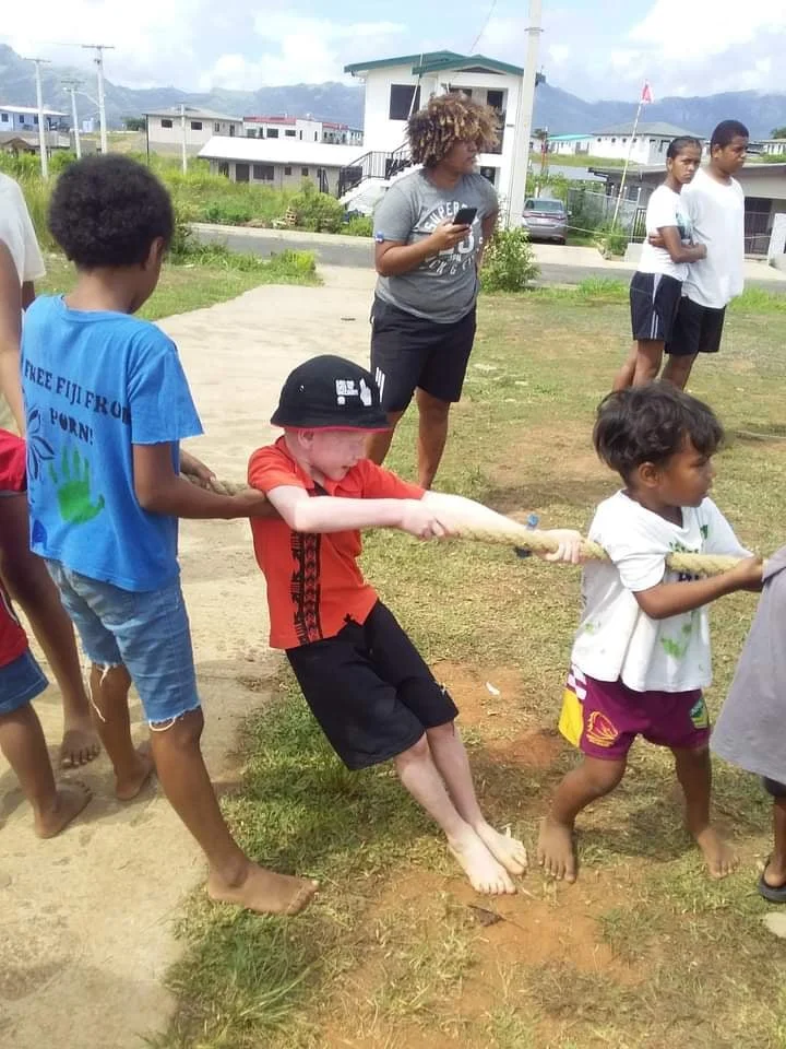 Children of different backgrounds playing tug-of-war outdoors